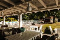 a patio with white chairs and a table and a roof at Jabłoń Lake Resort in Pisz