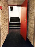a hallway with a staircase with a red door and stairs at Hotel Salea in Pornic