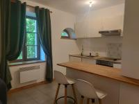 a kitchen with a counter and chairs and a window at La Jolie Dourbie de Nant in Nant