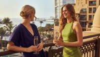 two women standing on a balcony with glasses of wine at Jumeirah Mina Al Salam Dubai in Dubai