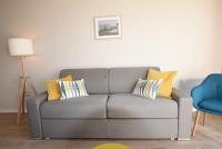 a gray couch with yellow pillows in a living room at Le Maginot, 1 chambre, garage, terrasse in Rennes