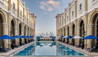 Blick auf den Innenhof eines Gebäudes mit Stühlen und Sonnenschirmen in der Unterkunft Oaks Ibn Battuta Gate Dubai in Dubai