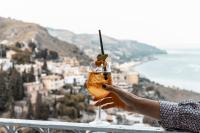 a hand holding a drink with a view of a city at Splendid Hotel Taormina in Taormina
