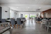 Un comedor con mesas y sillas y ventanas. en Logis Hôtel La crémaillère, en Hagetmau