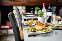 Una mesa con dos platos de comida y copas de vino. en Logis Hôtel La crémaillère, en Hagetmau
