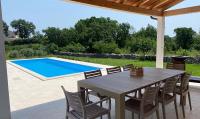 a patio with a table and chairs and a swimming pool at Villa Yucca Istra in Labin