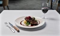 a plate of food on a table with a glass of wine at Mantra Bunbury in Bunbury