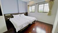 a bedroom with a bed with white sheets and two windows at Sun B&amp;B in Taitung City