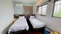two beds in a room with two windows at Sun B&amp;B in Taitung City