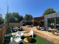 a patio with tables and chairs and a building at Paris Camping Ile du Roi in Triel-sur-Seine