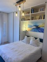 a bedroom with a white bed with a painting on the wall at Logement spacieux idéal famille in Marseille