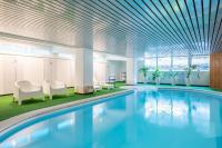a swimming pool in a building with white chairs and a ceiling at Grand Hôtel Des Templiers in Reims