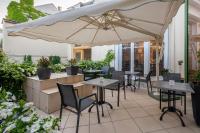 a patio with tables and chairs and an umbrella at Grand Hôtel Des Templiers in Reims