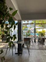 una habitación con mesas y sillas y una piscina en Hôtel Le Grand Bleu, en Saint-Gilles-les-Bains