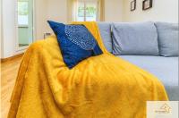 a yellow blanket on a couch with a blue pillow at Le Mykonos¶ Gare¶ 2Garages ¶Jardin ¶Spacieux in Grenoble