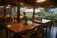 a restaurant with wooden tables and chairs and a man in the background at Jack Ecolodge - Lam Thuong Valley in Lung Co (1)