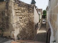 an alley with a stone wall next to a building at Small holiday home with courtyard, Bellegarde in Bellegarde
