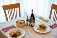 a table with two plates of food and a bottle of wine at Hotel Olympus in Caorle