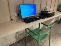 a desk with a computer monitor and a green chair at Yomi Hotel - ShuangLian MRT in Taipei