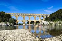 a bridge over a river with people in a boat at Gite de la tour, proche Nîmes ,Avignon in Montfrin