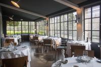 a restaurant with white tables and chairs and windows at Baumanière - Les Baux de Provence in Les Baux-de-Provence