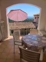 a table and chairs with a pink umbrella on a balcony at les Restanques Du Golf de Saint Tropez, 83310 Grimaud, France Appartement in Grimaud