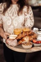 Una mujer sosteniendo una bandeja de comida con pan y carnes. en Hotel bij Jacob, en Enschede