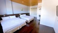 two beds in a hotel room with white sheets at Sun B&amp;B in Taitung City