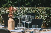 una mesa con copas de vino y un jarrón con flores en Hôtel Les Jardins de Deauville, en Saint-Martin-aux-Chartrains