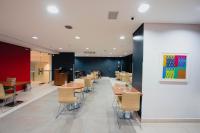 ibis Curitiba Shopping في كوريتيبا: غرفة طعام مع طاولات وكراسي ولوحة فنية