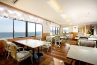 a restaurant with tables and chairs and a view of the ocean at Inatori Tokai Hotel Yuen in Higashiizu