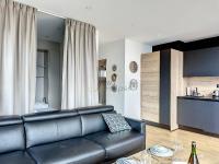 sala de estar con sofá de cuero negro y cocina en Le Yacht YourHostHelper, en Deauville