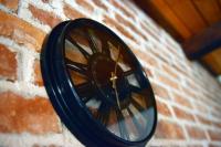 a black clock on the side of a brick wall at Kuća za odmor Čanić gaj in Gospić