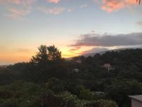 a sunset over a hill with trees and a house at Cocooning Tropic Studio avec Jacuzzi privatif in Saint-Louis