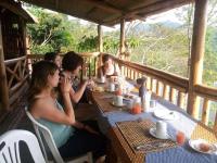 Un grupo de personas sentadas en una mesa en un porche. en Dave the Cave Eco Lodge and Cultural Campsite, en Rubirizi