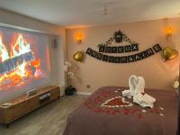 a bedroom with a large tv and a bed with a flower arrangement at BIOTY CHILL &amp; SPA in Le Blanc-Mesnil
