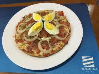 a pizza on a white plate with eggs on it at Espaço 345 Hotel Paulinia - Próximo Theatro Municipal in Paulínia