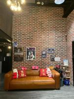 a brown leather couch in a room with a brick wall at Angels Hostel Taipei Ximen in Taipei