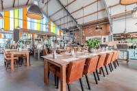 ein Restaurant mit Holztischen und -stühlen und Fenstern in der Unterkunft Hajé Nieuwegein in Nieuwegein
