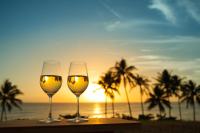 two wine glasses sitting on a table with the sunset at El Caminante Bar & Bungalows in Dana Point