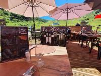 einen Tisch mit einem Glas Wein auf einem Tisch mit Sonnenschirmen in der Unterkunft Le Cosy Liberty in Ustou