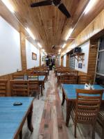 uma fileira de mesas e cadeiras em um restaurante em Hotel CM Palace - Pure Vegetarian em Ner Chowk