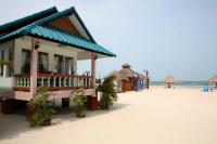 a building on the beach with the ocean in the background at Nice Sea Resort in Srithanu