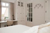 a white bedroom with a white bed and a window at B&amp;B - Ter Douve in Dranouter