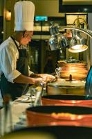 a chef preparing food in a restaurant kitchen at Pelangi Beach Resort & Spa, Langkawi in Pantai Cenang