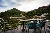 a table and chairs on a balcony with a mountain at Shabby Home 28 in Jiufen