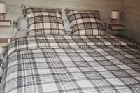 a bed with a plaid blanket and two pillows at MAISON &amp; PISCINE PRIVES,PLAGES OCEAN ET LAC A 10 kms in Linxe