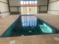 a swimming pool in a building with blue water at Gîtes du Grand Air in Saint-Michel-en-lʼHerm