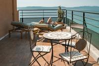 a woman laying on a balcony with a table and chairs at Surplage Hotel Cavalière in Le Lavandou