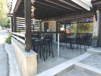 un patio con sillas negras, mesas y ventanas en Karlovasi Studios, en Karlovasi